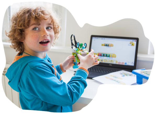 A child holding a learning model beside a laptop.